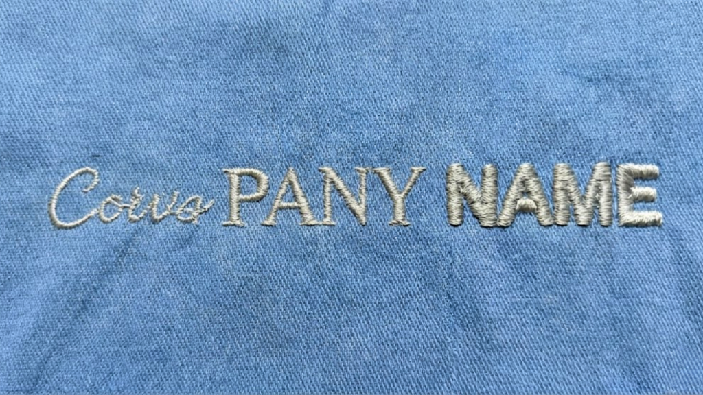 Embroidered text on denim fabric showing correct satin stitch thickness and pull compensation