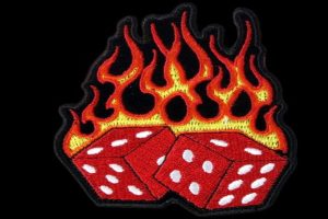Digital embroidery file of two red dice with orange and yellow flames on a black background.
