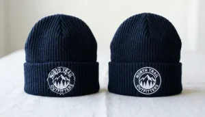 Two knit beanies side by side showing embroidery with and without knockdown stitch results
